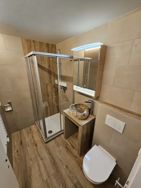 Douche en bois clair et vasque en pierre naturelle beige