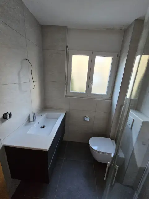 Vasque sur plan bois, WC et douche près de la fenêtre
