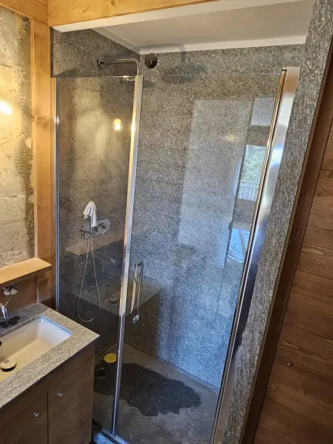 Douche en granit dans un chalet, paroi vitrée