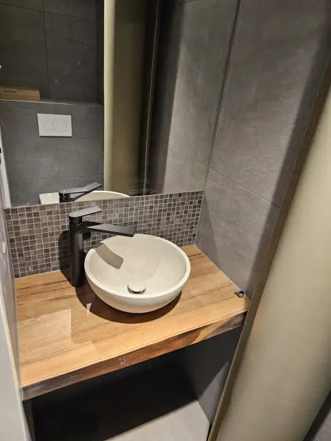 Vasque en pierre claire et robinetterie noire sur mosaïque
