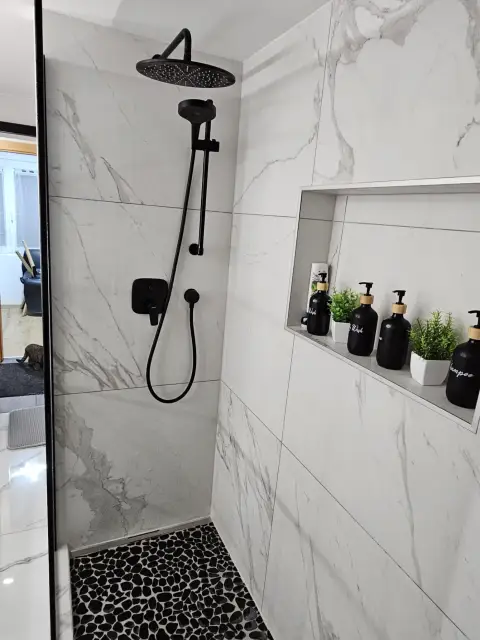 Douche en marbre blanc, robinetterie noire, niche de rangement
