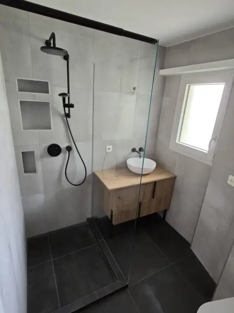 Douche avec niches de rangement carrelées et vasque blanche suspendue