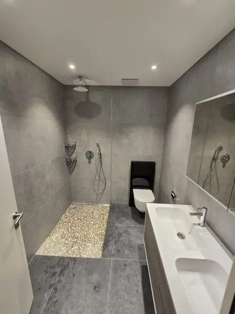 Douche vitrée avec sol en galets et vasque rectangulaire sur meuble bois